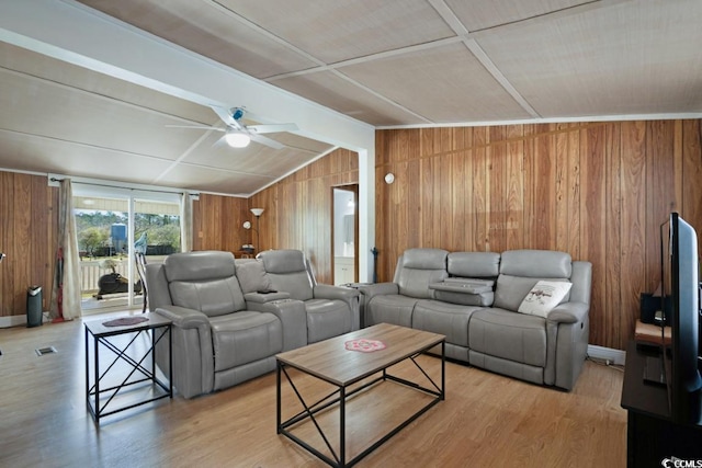 living room featuring visible vents, vaulted ceiling with beams, wood walls, light wood-style floors, and a ceiling fan