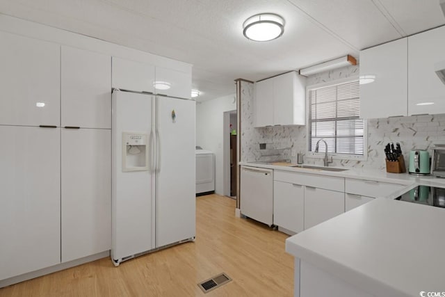 kitchen with a sink, visible vents, white appliances, and white cabinets