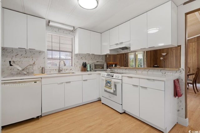 kitchen featuring a sink, under cabinet range hood, white appliances, light wood finished floors, and light countertops