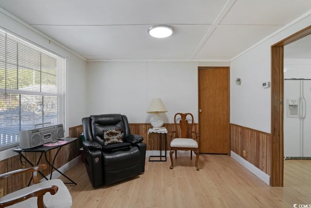 sitting room with crown molding, wood finished floors, a wainscoted wall, and wood walls