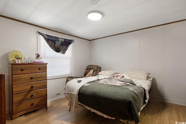 bedroom with light wood finished floors, baseboards, and ornamental molding