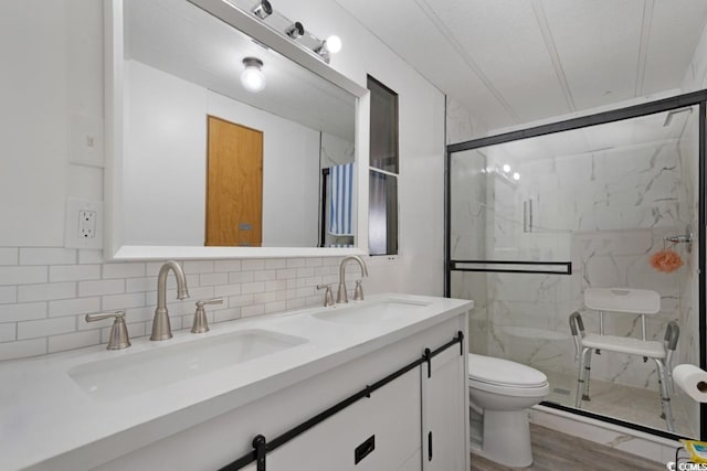 full bath with a sink, decorative backsplash, toilet, and a marble finish shower