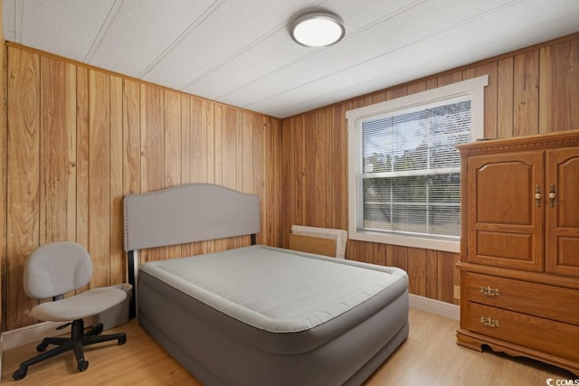 bedroom featuring wooden walls and light wood-style floors