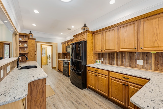 kitchen with light stone countertops, light wood-style flooring, brown cabinetry, black appliances, and a sink