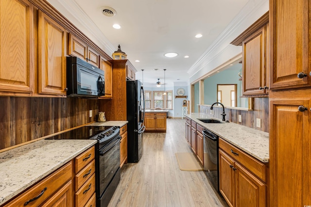 kitchen featuring visible vents, black appliances, ornamental molding, a sink, and light stone counters