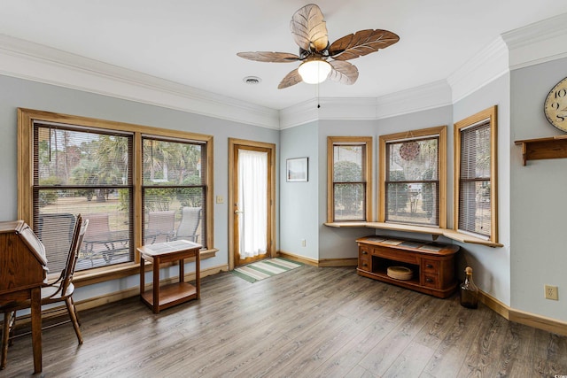 interior space featuring a ceiling fan, wood finished floors, baseboards, and ornamental molding