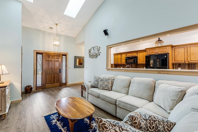 living room with a skylight, baseboards, wood-type flooring, and high vaulted ceiling