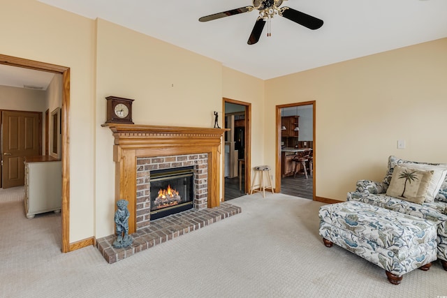 living room with a brick fireplace, baseboards, carpet, and a ceiling fan