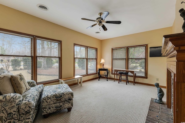 living area featuring visible vents, ceiling fan, baseboards, carpet floors, and a fireplace