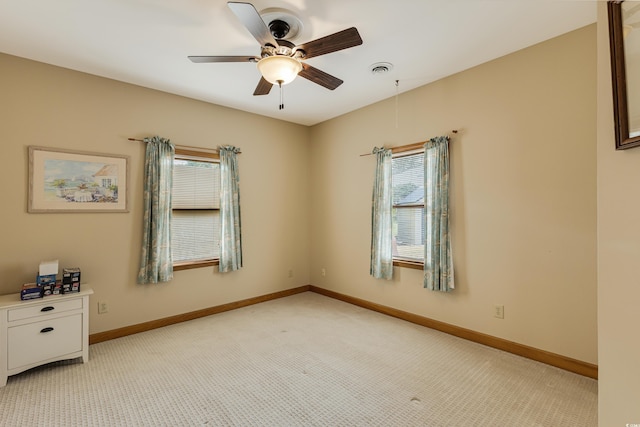 empty room featuring baseboards, light carpet, visible vents, and ceiling fan