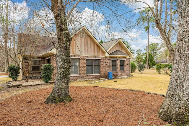 rear view of house with a yard, brick siding, and roof with shingles