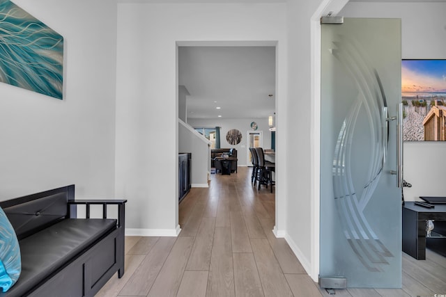 corridor with baseboards and light wood-type flooring