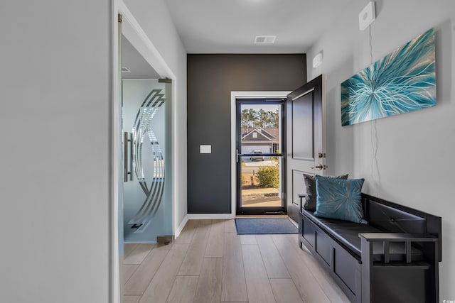 foyer featuring light wood finished floors, visible vents, and baseboards