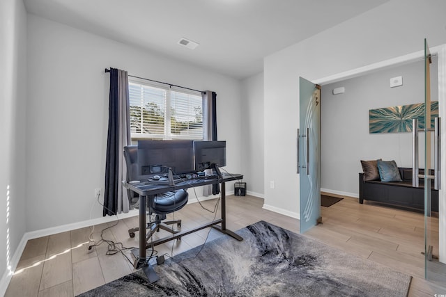 office space featuring wood finish floors, visible vents, and baseboards