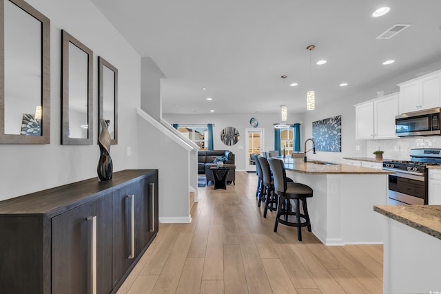 kitchen with a sink, light stone countertops, white cabinetry, and stainless steel appliances