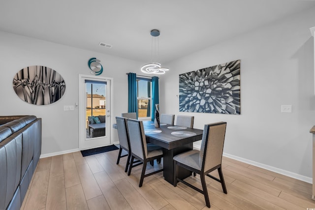 dining space featuring light wood-style floors, visible vents, and baseboards