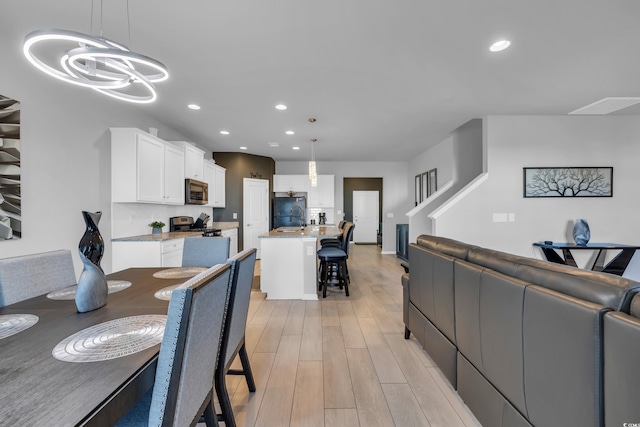 dining space featuring light wood-style flooring, recessed lighting, visible vents, and a chandelier