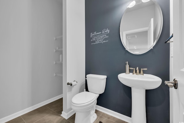 bathroom featuring tile patterned floors, visible vents, toilet, a sink, and baseboards