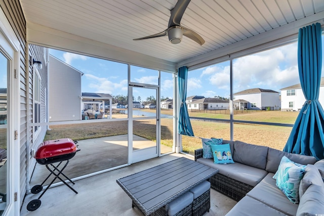 sunroom / solarium with a ceiling fan, a healthy amount of sunlight, and a residential view