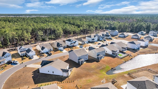 drone / aerial view featuring a residential view, a wooded view, and a water view