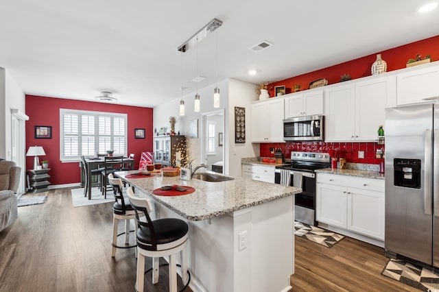 kitchen featuring a sink, dark wood finished floors, white cabinetry, appliances with stainless steel finishes, and decorative backsplash