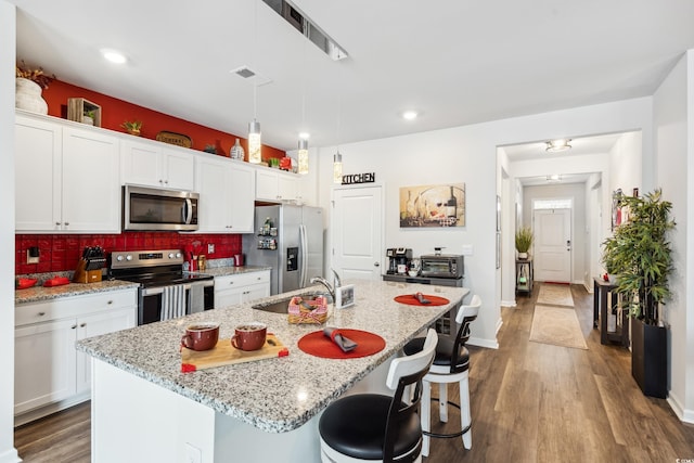 kitchen with visible vents, a sink, stainless steel appliances, a kitchen bar, and tasteful backsplash