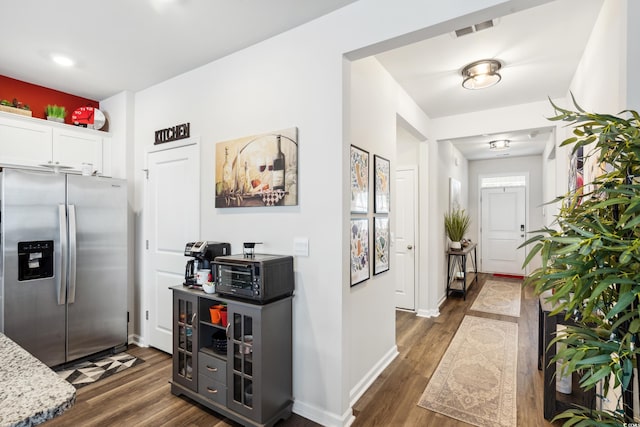 kitchen featuring visible vents, a toaster, stainless steel fridge with ice dispenser, dark wood-style flooring, and white cabinetry