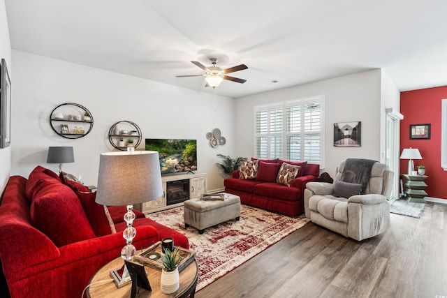 living area featuring a fireplace, ceiling fan, and wood finished floors