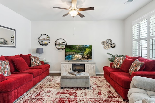 living area with visible vents, baseboards, a ceiling fan, and wood finished floors