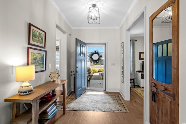 entryway with a notable chandelier, wood finished floors, baseboards, and ornamental molding