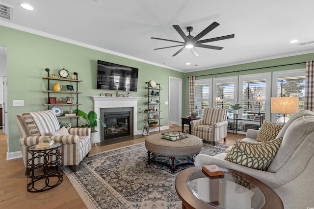 living area featuring a fireplace with flush hearth, visible vents, and ornamental molding