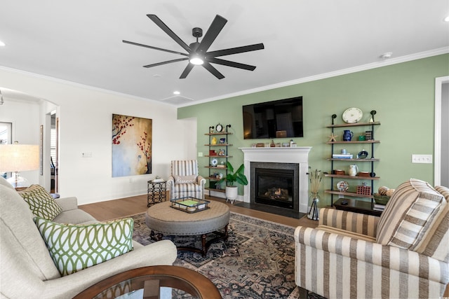 living area with wood finished floors, baseboards, a fireplace with flush hearth, arched walkways, and ornamental molding