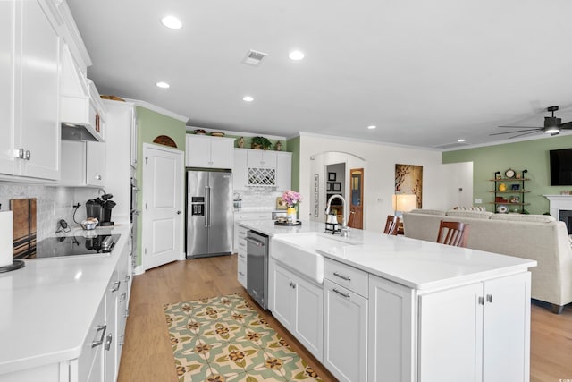 kitchen featuring a sink, white cabinetry, crown molding, black electric cooktop, and high quality fridge