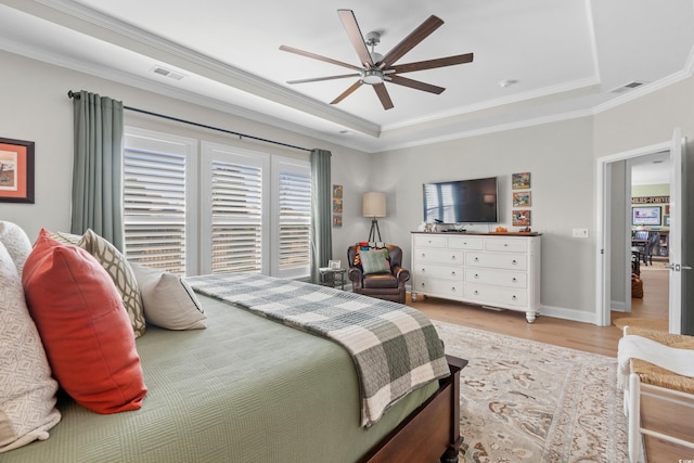 bedroom featuring a tray ceiling, crown molding, light wood-style floors, and visible vents