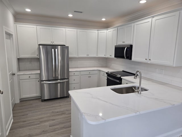 kitchen with visible vents, a peninsula, freestanding refrigerator, a sink, and black range with electric cooktop