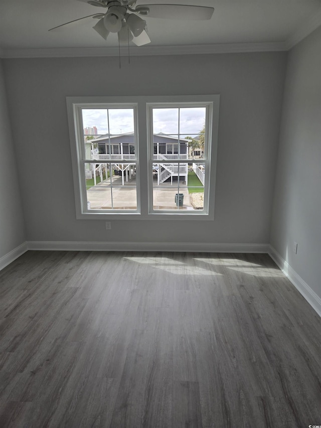 empty room with dark wood-style floors, baseboards, ornamental molding, and a ceiling fan