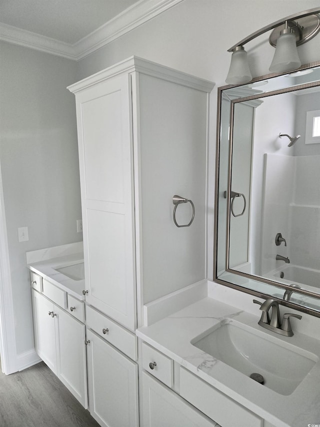 bathroom featuring wood finished floors, shower / washtub combination, ornamental molding, and vanity