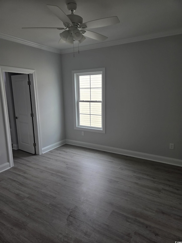 spare room with dark wood finished floors, crown molding, a ceiling fan, and baseboards