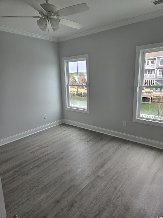 empty room featuring visible vents, baseboards, ornamental molding, and dark wood-style flooring