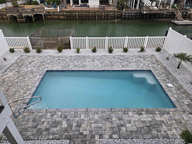 view of pool with a patio area, a fenced in pool, a fenced backyard, and a water view