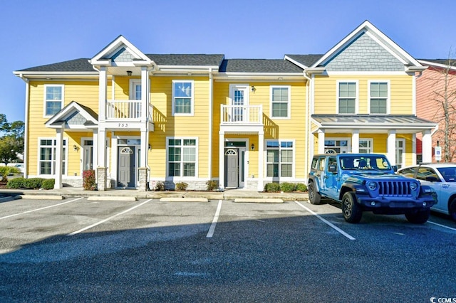 townhome / multi-family property featuring a shingled roof and uncovered parking