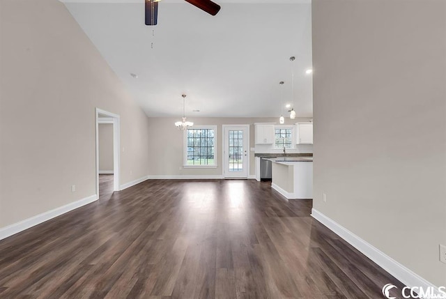 unfurnished living room with baseboards, dark wood-style flooring, and ceiling fan with notable chandelier