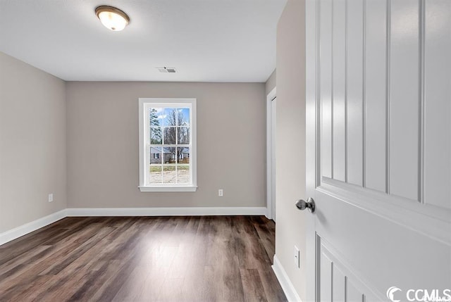 empty room with visible vents, baseboards, and dark wood-style flooring