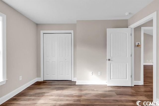 unfurnished bedroom featuring a closet, baseboards, and wood finished floors