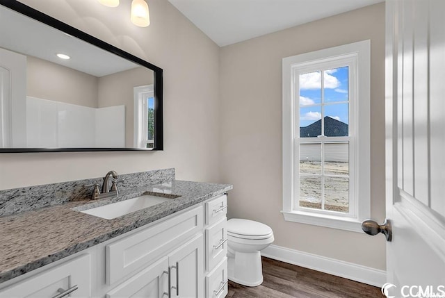 bathroom featuring plenty of natural light, toilet, and baseboards