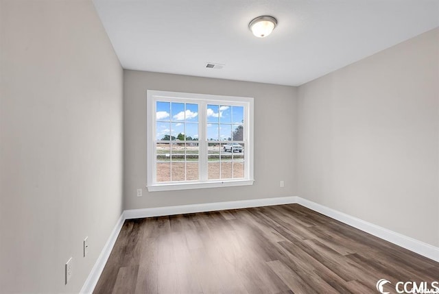 unfurnished room with visible vents, baseboards, and dark wood-style flooring