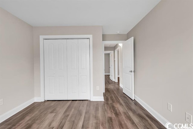 unfurnished bedroom featuring a closet, baseboards, and wood finished floors