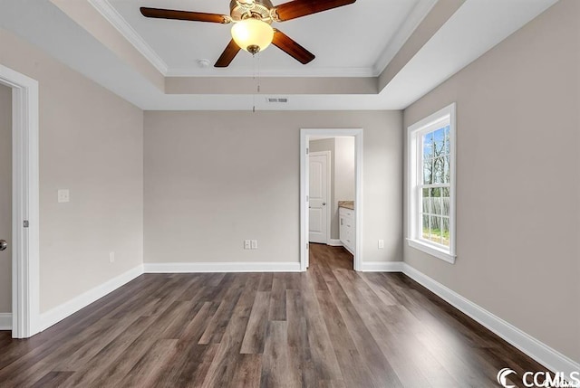 spare room with a tray ceiling, baseboards, visible vents, and dark wood-style flooring