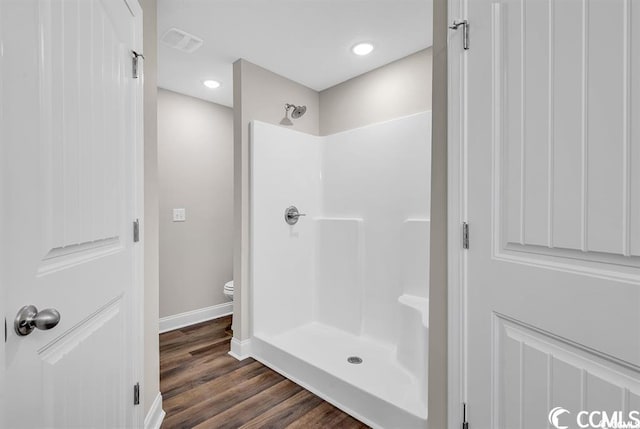 full bath with visible vents, toilet, wood finished floors, baseboards, and walk in shower