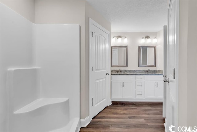 bathroom featuring a textured ceiling, double vanity, wood finished floors, and a sink